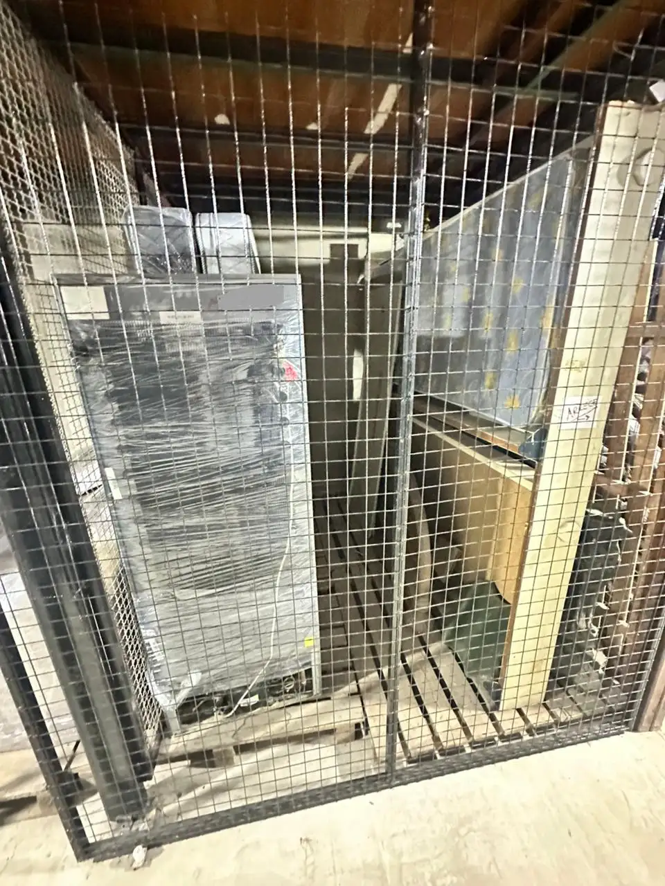 Detalle de guardamuebles ventilado mediante rejas, mostrando electrodomésticos y colchones estibados correctamente.