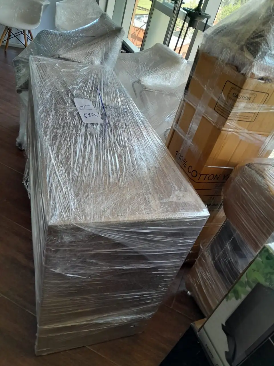 Mueble de madera tipo vajillero protegido con múltiples capas de film stretch para asegurar puertas y cajones durante el transporte.