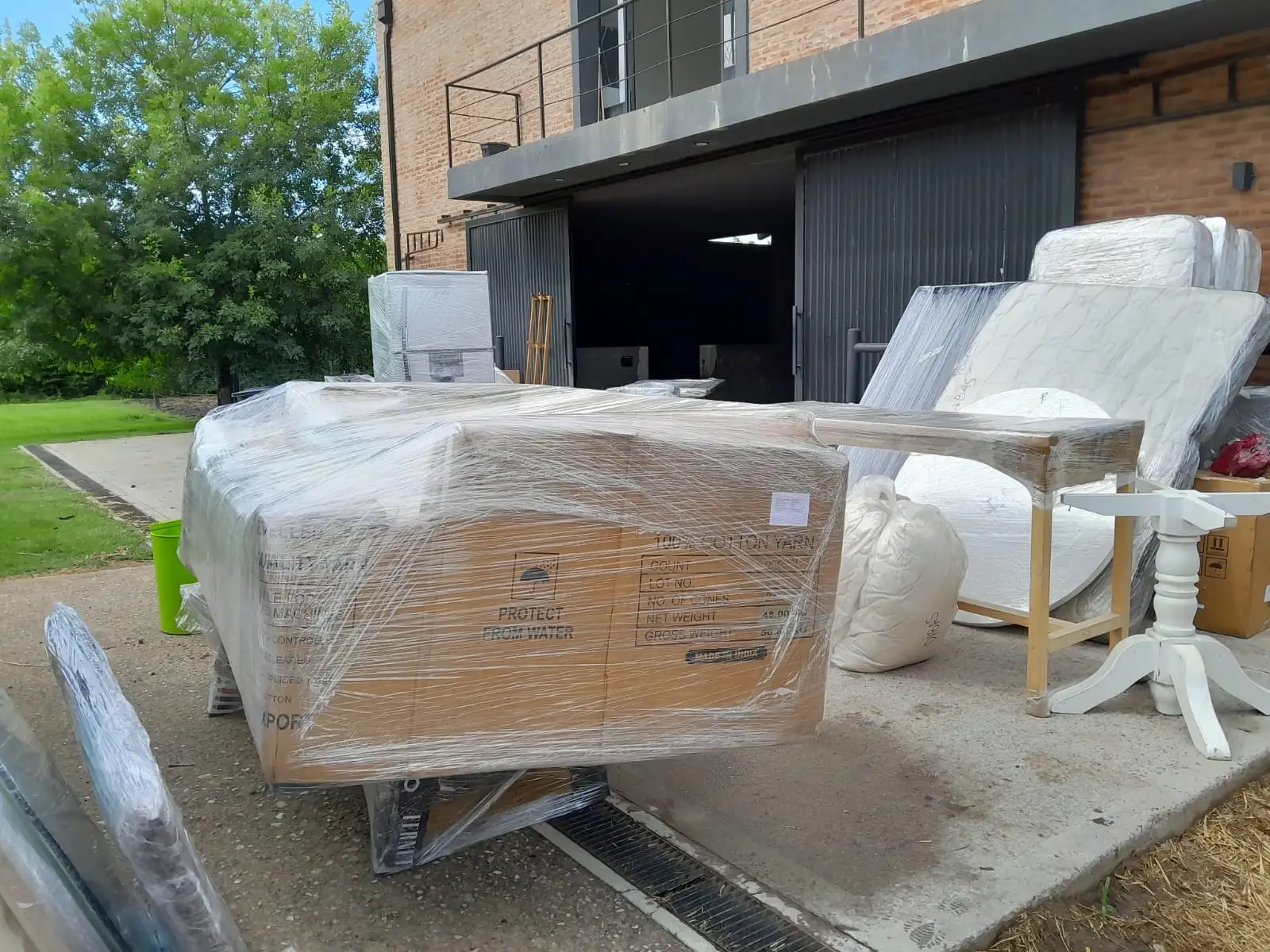 Grandes muebles embalados con protección impermeable listos para la carga en camión en una mudanza de casa en barrio cerrado.
