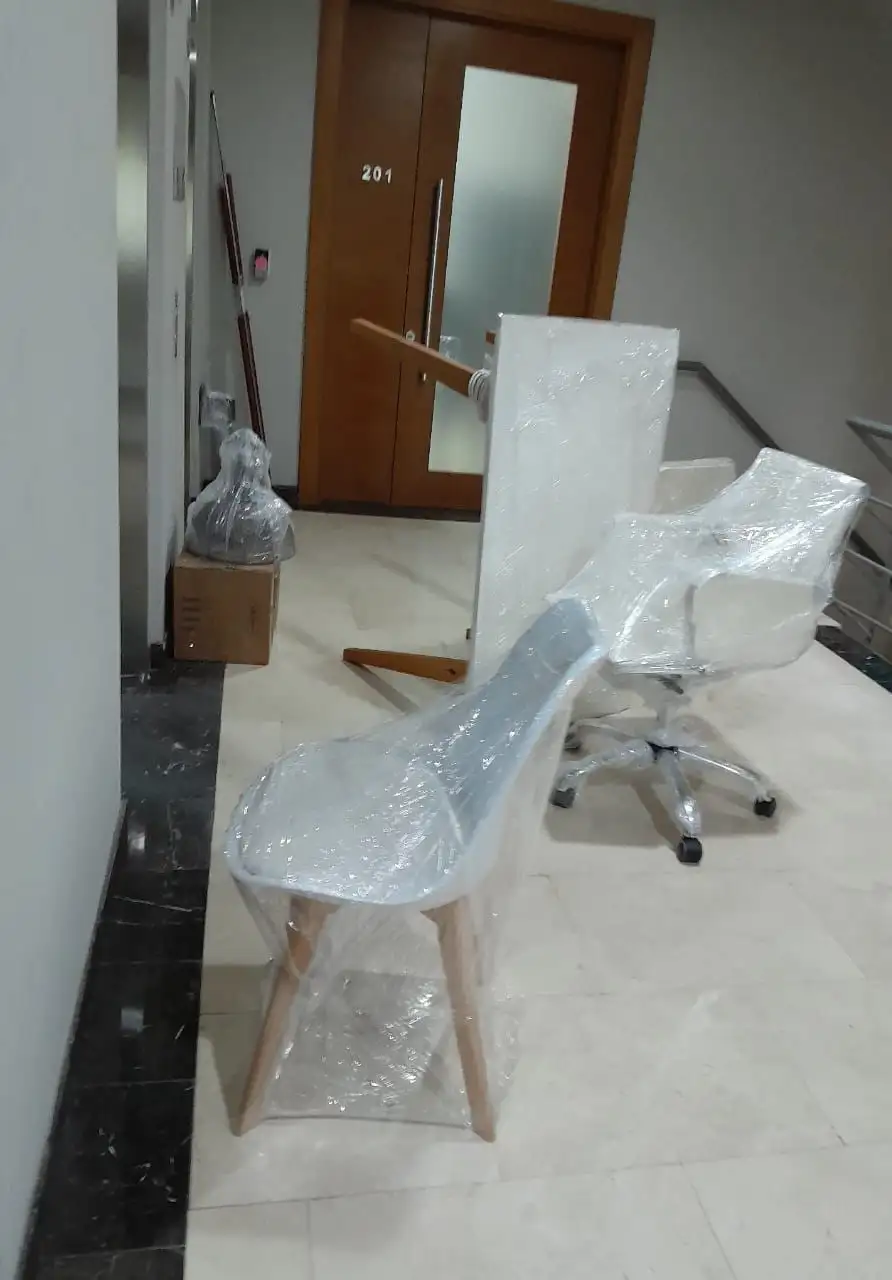 Silla de diseño moderna envuelta meticulosamente en plástico protector para evitar rayaduras y roces durante la carga.