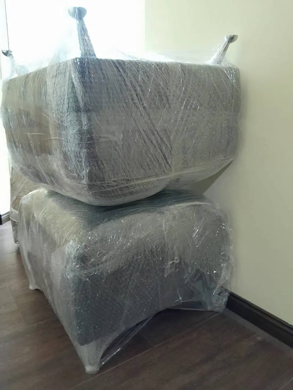 Par de sillones tapizados totalmente envueltos en film stretch industrial para proteger la tela contra polvo y manchas durante la mudanza.