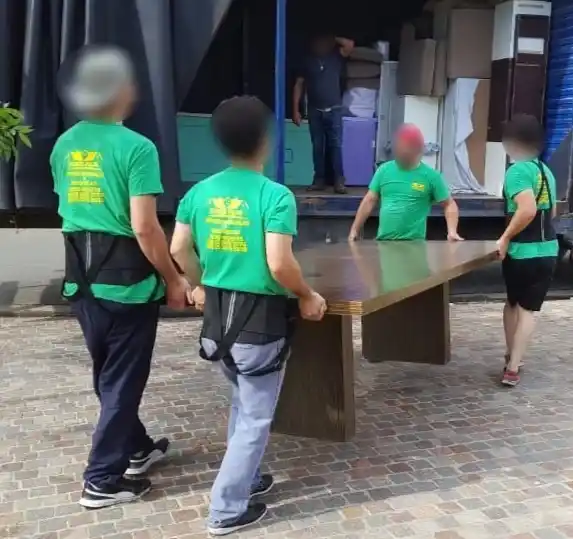 Equipo de Guardamuebles y Mudanzas - Boxes Pilar cargando una mesa de comedor pesada hacia el camión de mudanzas en Zona Norte