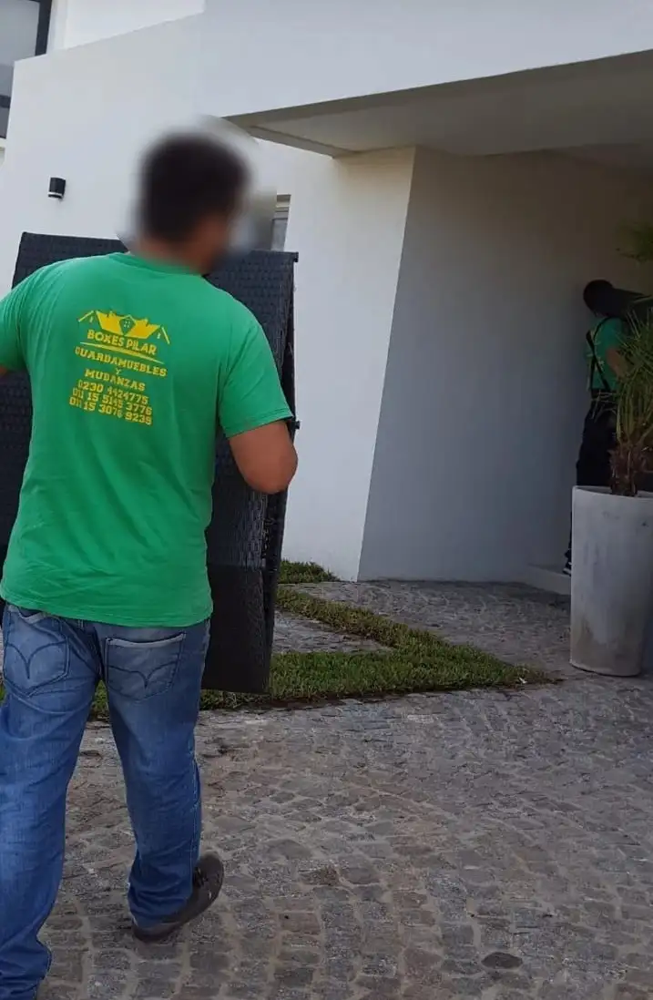 Operario ingresando mobiliario embalado y protegido a una residencia moderna en Pilar.