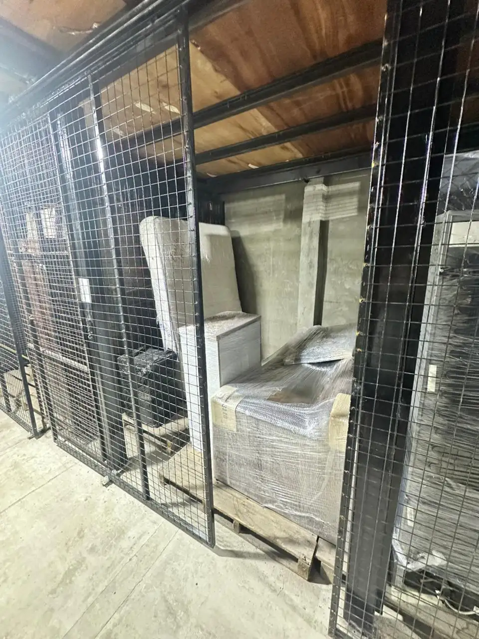 Almacenamiento de sofá y colchón embalados profesionalmente y elevados sobre tarimas de madera para evitar humedad del suelo.