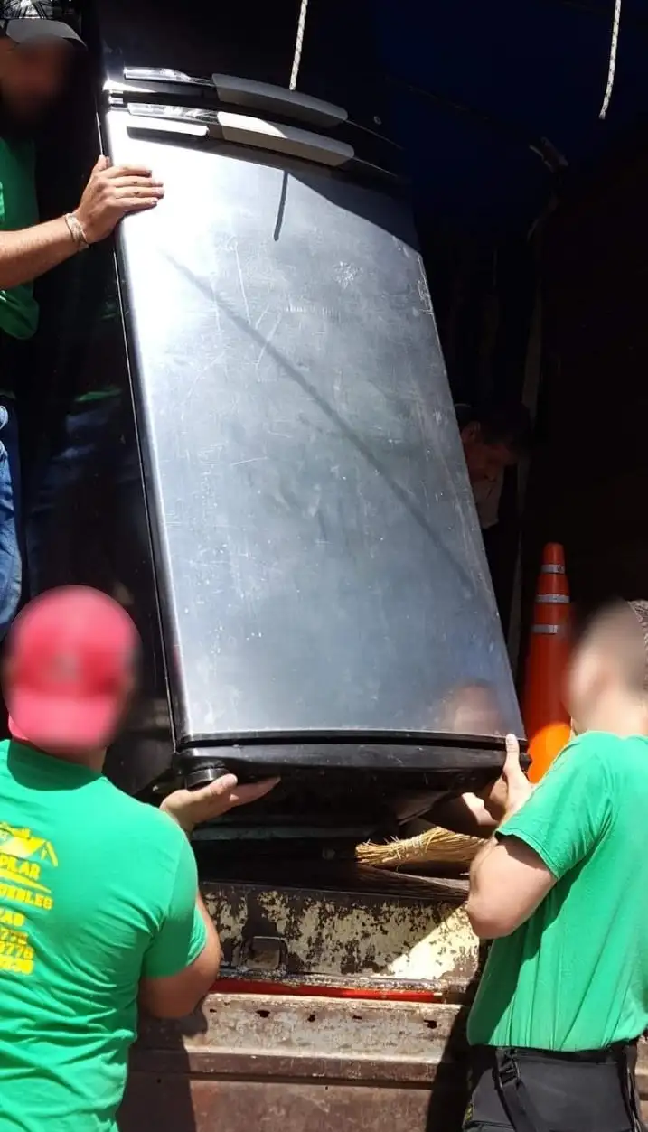 Carga cuidadosa de una heladera grande al camión de fletes utilizando técnicas de elevación segura por personal capacitado.